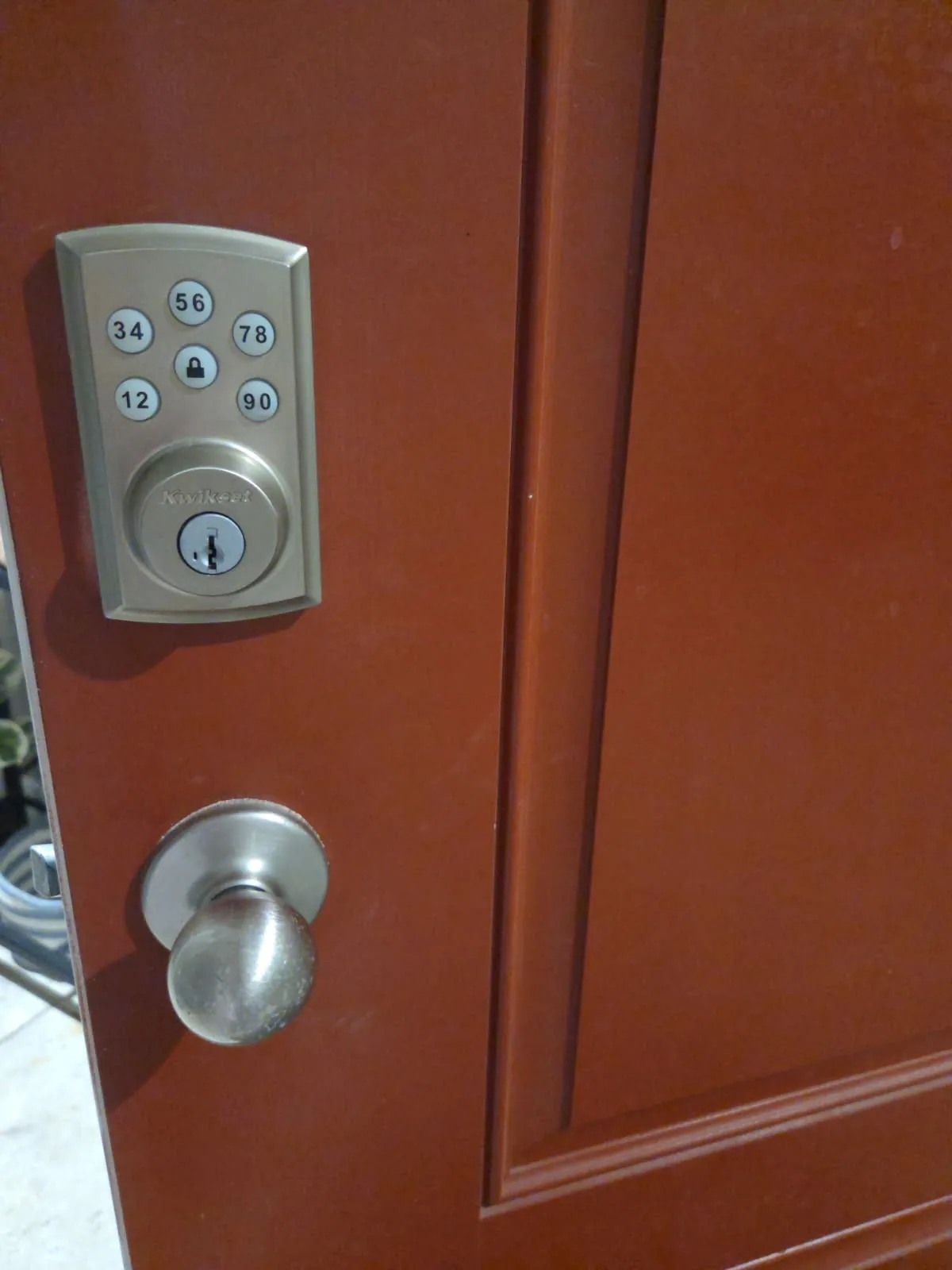 Kwikset keypad smart deadbolt newly installed on a red residential front door