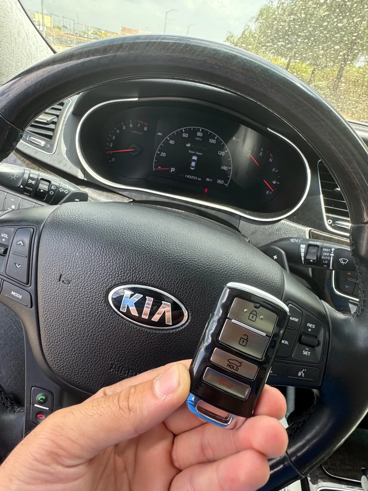 New Kia smart proximity key held in front of a Kia steering wheel after mobile replacement service