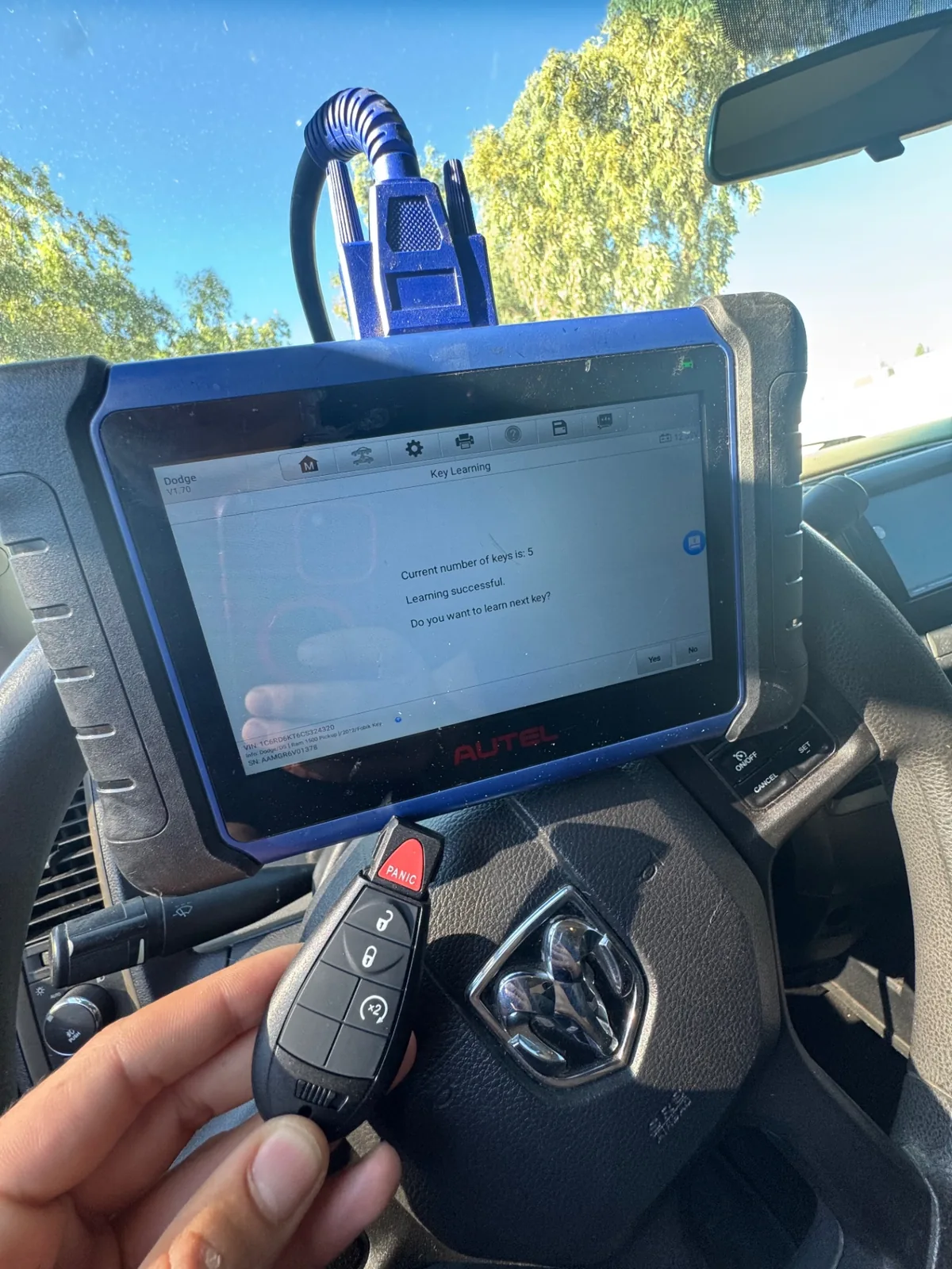 Dodge key programming in progress with diagnostic tablet and new remote key inside the vehicle