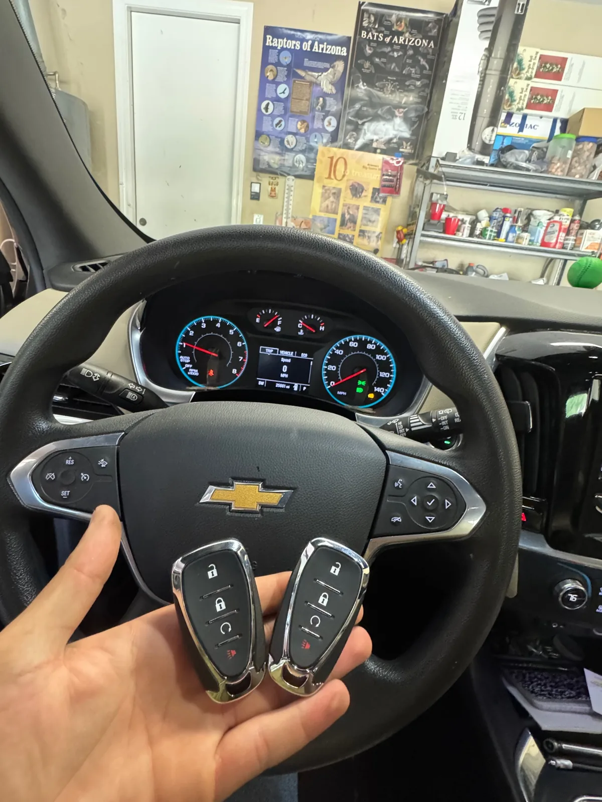 Two replacement Chevrolet remote keys shown in front of a Chevy steering wheel during a real service visit