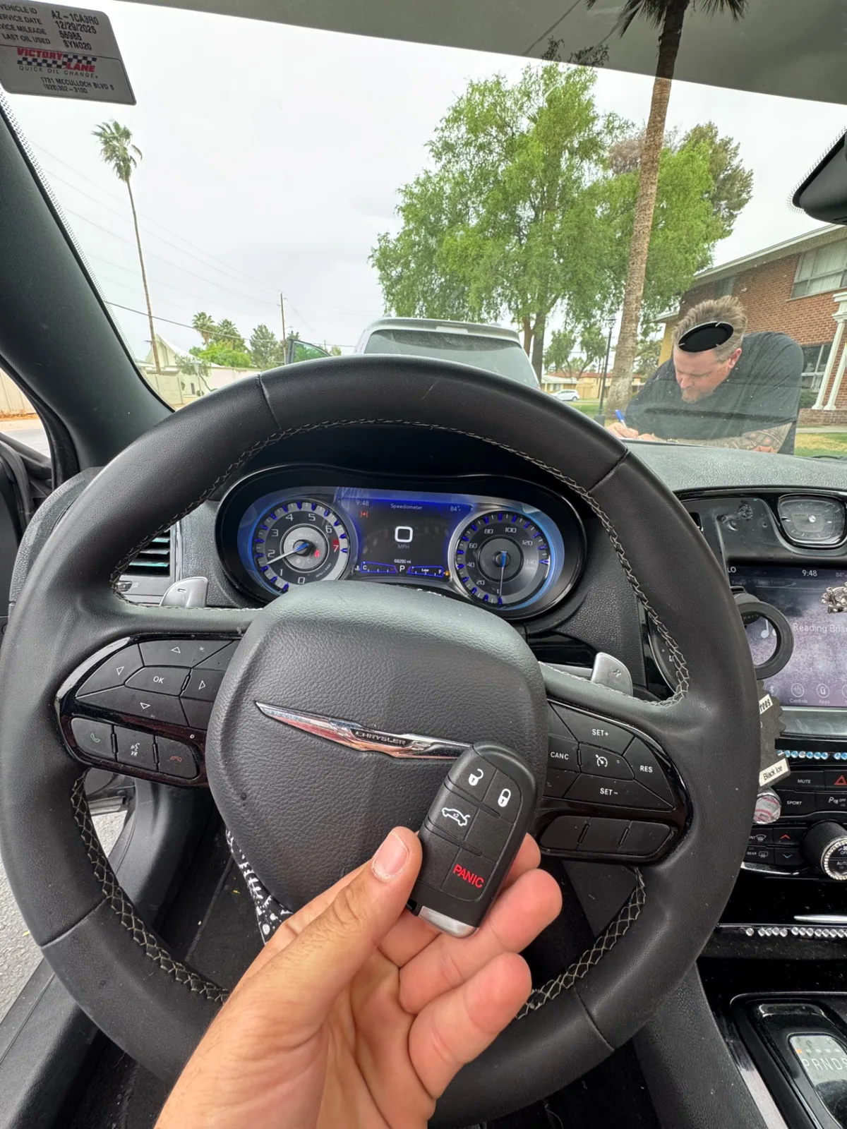 New Chrysler remote key held in front of a Chrysler steering wheel during a real on-site programming job